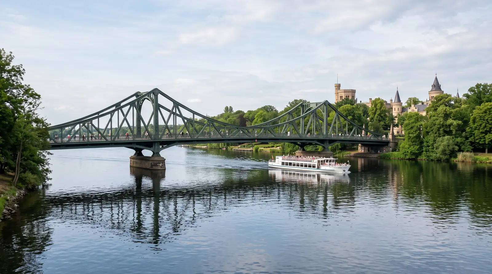 Grand bridge toward Potsdam parkland with a passing boat